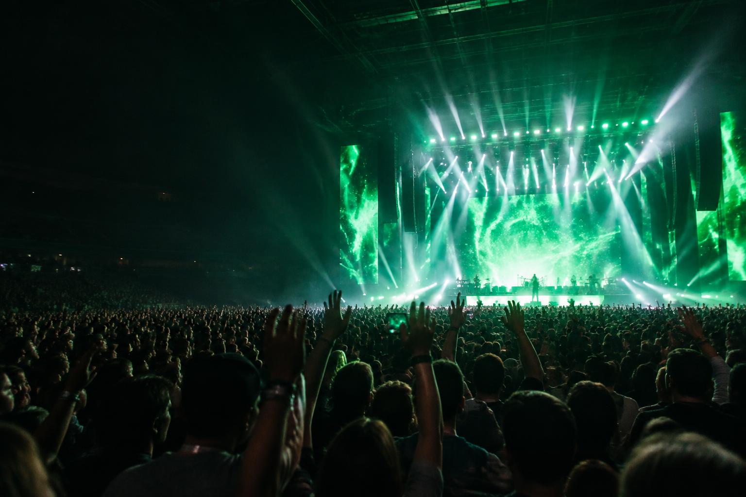 A crowd gathers in front of a live stage illuminated in green